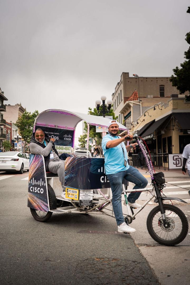 A laughing rider and his driver in a Cisco wrapped pedicab in the Gaslamp Quarter