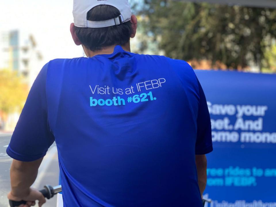 Back of a driver's shirt printed Visit us at IFEBP booth 621